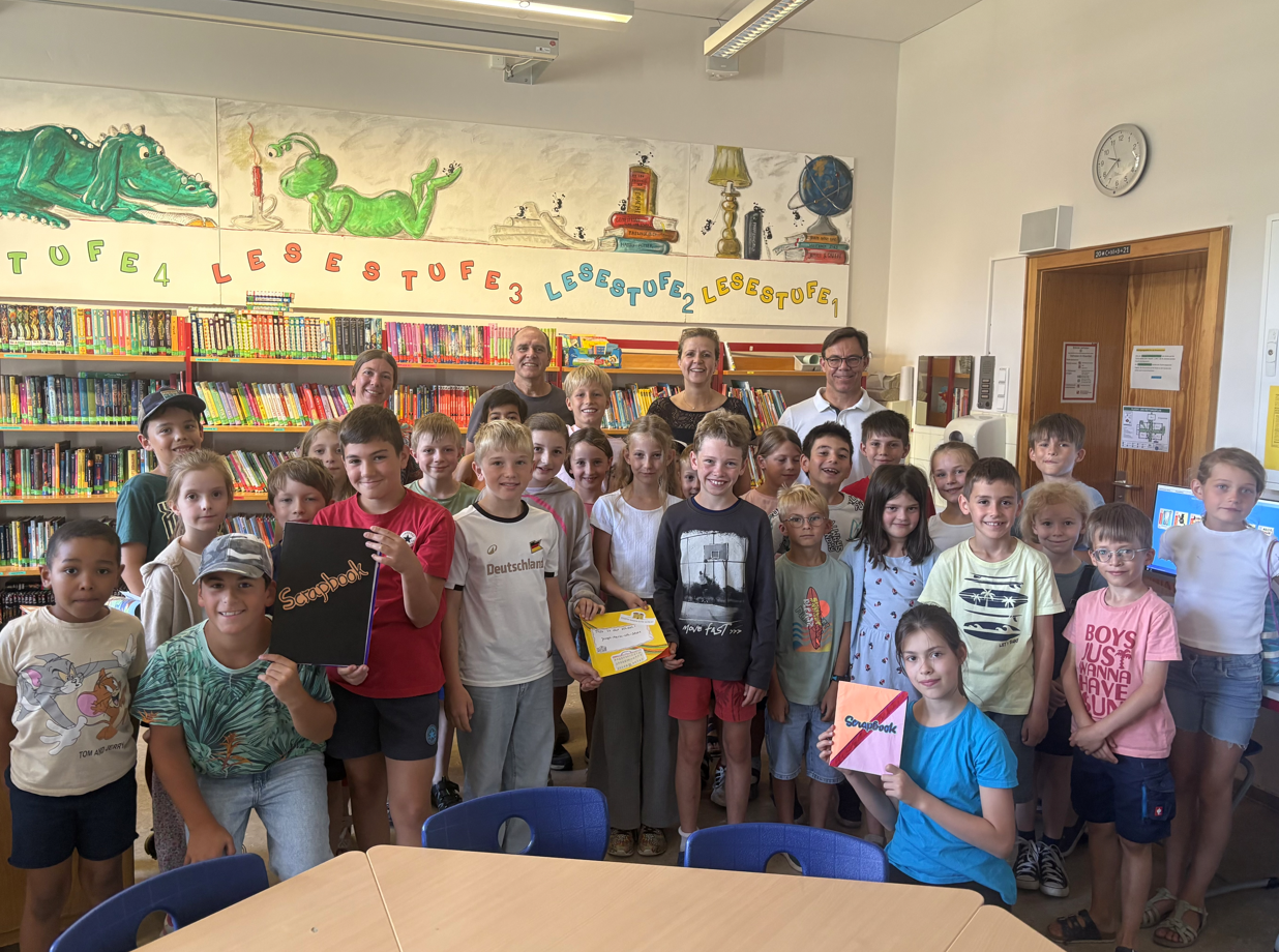 Gemeinschaftsprojekt: Kinder, Lehrer und Fördervereins-Vorsitzender Martin Rohrmann übergeben das interkulturelle Bilderbuch an Mario Dietrich, der die Post persönlich überbringt.